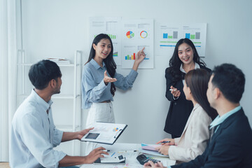 Team Meeting: A diverse team of Asian business professionals engaged in a productive meeting, analyzing data and collaborating on strategies. The image embodies the spirit of modern business.