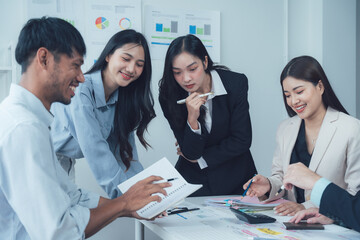 Collaborative Business Meeting: A diverse team of young professionals engages in a productive brainstorming session, reviewing documents and charts, fostering collaboration and innovative ideas.