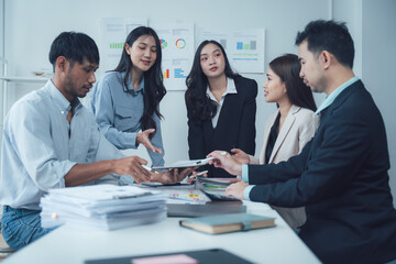Collaborative Brainstorming: A diverse group of professionals engage in a lively discussion around a table, surrounded by charts and data, showcasing the dynamic energy of a modern workplace.