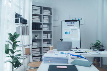 Modern Office Workspace: A minimalist office interior with a white desk, laptop, whiteboard, and potted plants.  The space is clean, organized, and inviting, perfect for a productive work environment.