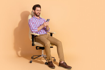 Photo of handsome ecommerce entrepreneur wearing formal clothes sit chair chatting phone isolated...