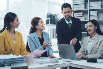 Teamwork Makes the Dream Work: A collaborative meeting of Asian business professionals in a modern office setting, focused on a laptop and paperwork, reflects dedication, strategy, and success.