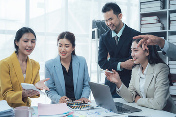 Teamwork Makes the Dream Work: A group of smiling Asian business professionals collaborates effectively around a laptop in a modern office setting.  The image exudes positivity, productivity.