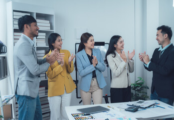 Business Team Applauding Success: A diverse group of colleagues gather in a modern office setting, their hands clapping in unison as they celebrate a shared achievement.