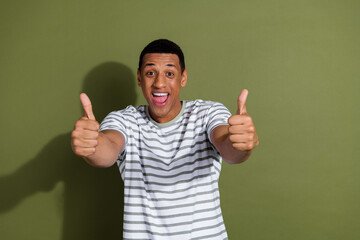 Naklejka premium Photo portrait of nice young male excited thumb up wear trendy striped white outfit isolated on khaki color background