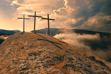 Three wooden crosses on hill against sky. Biblical scene, concept of Crucifixion on Mount Golgotha,...