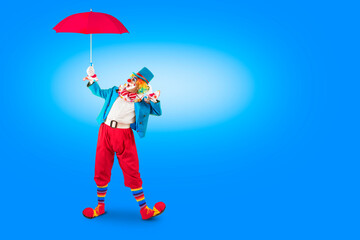 Surprised clown holding umbrella. Entertainer Joker in colorful suit and wig. Buffoon with clown...