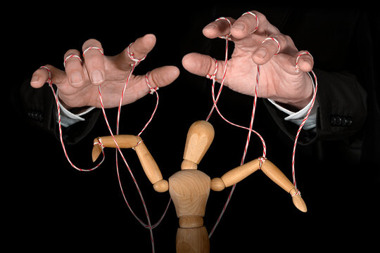Wooden puppet doll, obeying master  hand pulling the strings of dancing marionette