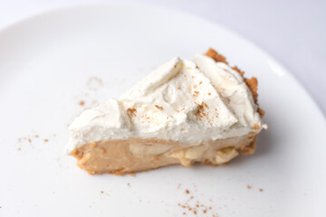 A piece of banoffee banana pie with caramel sauce and cheese cream on the white background. Traditional english cake. Ready to eat. Cooking concept