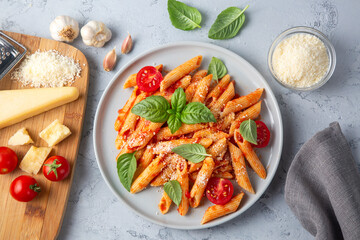 Classic italian pasta penne alla arrabiata with basil and freshly grated parmesan cheese on dark table. Penne pasta with chili sauce arrabbiata.