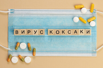 Вирус Коксаки - Coxsackievirus in Russian, spelled with wooden cubes on a surgical mask, surrounded by pills.