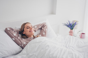 Young woman enjoying a peaceful morning in cozy bed with natural light streaming in the bedroom