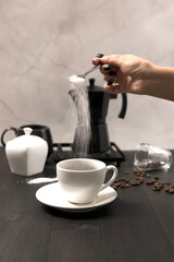 
Black coffee is poured into a cup, on a black background. pour milk into coffee