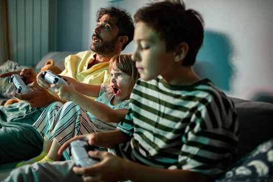 Father and kids playing video games on the couch at home