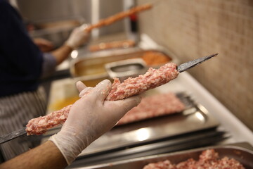 A close-up of a chef preparing a traditional Turkish kebab, skewering marinated meat for grilling