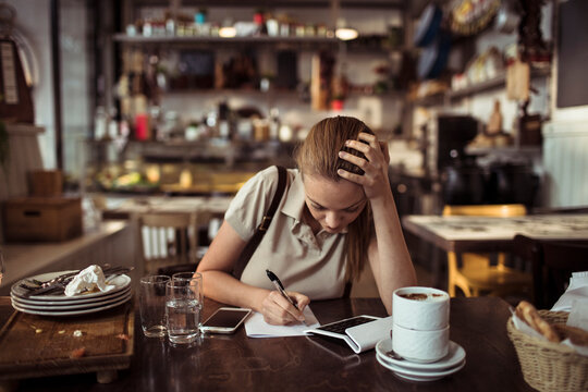 Waitress looking stressed while calculating bill at restaurant table