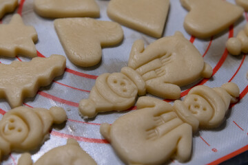 Close-up view of raw Snowman and Christmas tree shaped shortbread (or shortie) holidays cookies lying on baking tray before baking. Soft focus. copy space. Christmas food preparation theme.
