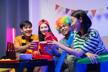 A group of excited Asian male and female friends watched the World Cup match on TV and drank beers and ate snacks together at home. Sports fans shout and celebrate the victory of their sports team.