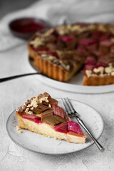 Rhubarb custard tart with geometric pattern and strawberry jam on a light stone table. A piece of cake. Spring and summer sweet-sour healthy dessert. Top view