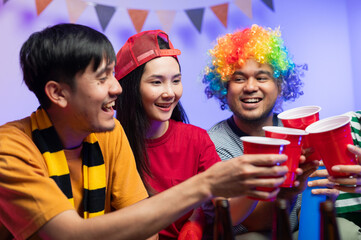 A group of excited Asian male and female friends watched the World Cup match on TV and drank beers and ate snacks together at home. Sports fans shout and celebrate the victory of their sports team.