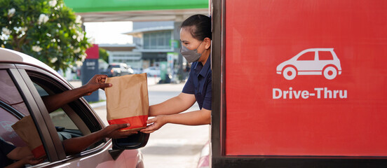 An African-American man receives a burger and soda snack in his car during rush hour from a female...