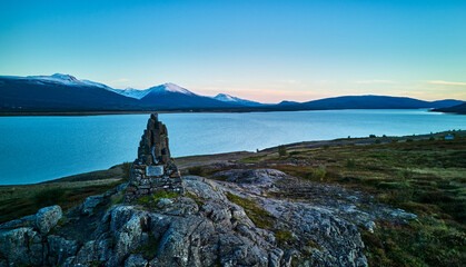 Sunset Monument by Icelandic Lake and Snowy Mountains