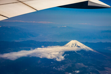 Mount Fuji seen from an airplane on a beautiful blue day with snow on the peak.