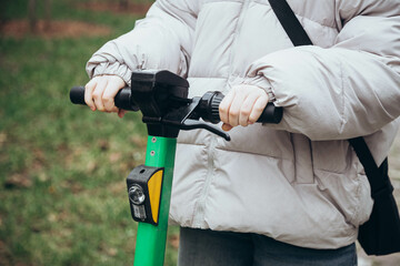 A girl using a rental service with an e-scooter in urban city street.