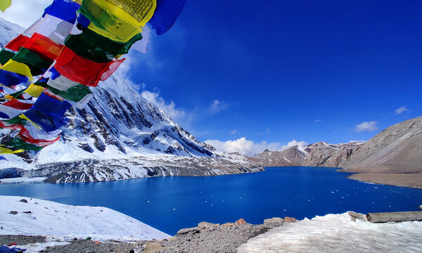 The breathtaking Tilicho Lake, framed by colourful prayer flags, sits peacefully amidst the snow-covered peaks of the Annapurna range.