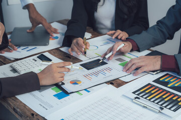 Business Analysis: A team of professionals gather around a table, reviewing financial data and...