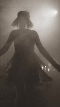 Old film 1920 style black white color, dark female silhouette dancing, sexy dress waving. retro lady happy woman at night club party have fun joy. room full smoke back light flare vertcal video crop