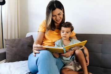 Mother and son sitting on the sofa reading a book