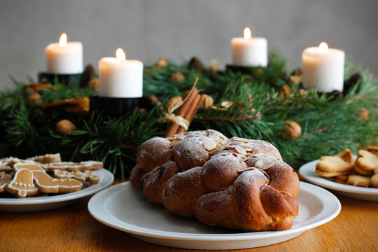Traditional Czech and Slovak Christmas sweet plaited bread called vanocka (in Slovak vianocka), Christmas cookies and a Christmas advent wreath with four burning candles on wooden table.