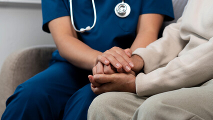 A female nurse caregiver holds hands to encourage and comfort an  people of retirement age Caregiver helping elderly woman provides medical advice