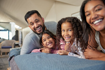 Portrait of smiling multiethnic family lying down on bed together