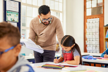 Teacher helping student in classroom during lesson