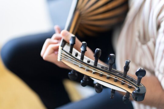 A detailed view of a musician&rsquo;s hand strumming the strings of atraditional oud instrument