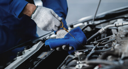 A mechanic is working on a car engine, using a blue cloth to wipe it down. Concept of precision and...