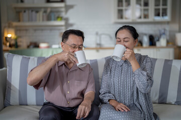An elderly couple enjoys a peaceful moment at home, sharing smiles and drinks. The warm and cozy atmosphere emphasizes their deep connection, happiness, and the comfort of spending time together.