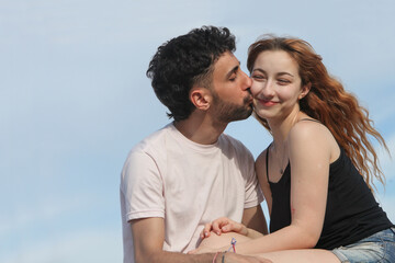 portrait of young cheerful loving couple on the beach with sky in background