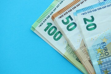 Big amount of one hundred, twenty and fifty euro money bills on blue background