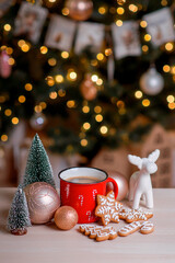 Red mug of hot cocoa with marshmallows and homemade Christmas gingerbread cookies. Christmas card with hot cocoa and golden bokeh