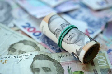Roll of 500 Ukrainian Hryvnia money bills lies on big pile of ukrainian currency money close up