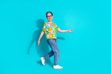 Full length portrait of pretty aged lady walk empty space isolated on turquoise color background