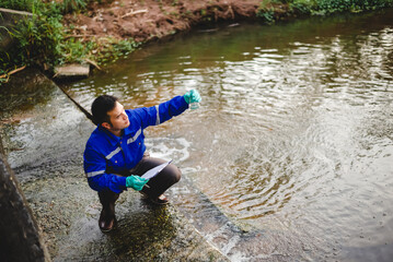 A water resource engineer checks the purity of water in a scientific glass bottle and records it on paper.