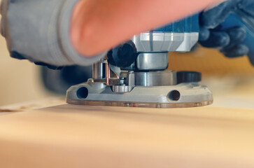 Handheld router tool shaping and smoothing wood edges, focus on skilled carpentry work