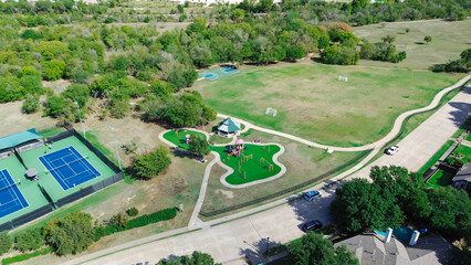 Large soccer fields and basketball courts in suburban recreational facility sport complex in Carrollton, Texas, tennis center with players practicing, shaded playground, walking pathway trails