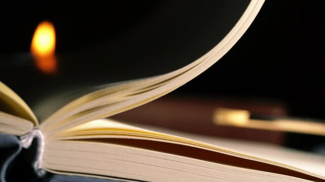 Pages turning on open book with candle light bokeh background
