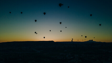 Many colorful hot air balloons flight above mountains - panorama of Cappadocia at sunrise. Wide landscape of Goreme valley in Cappadocia - billboard background for your travel concept in Turkey.