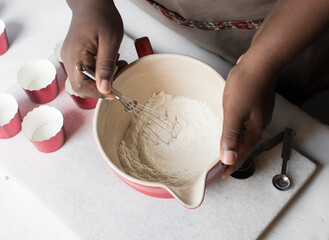Hand Whisking Vanilla ingredients for making cupcake batter in a red mixing bowl, process of making...